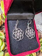 Load image into Gallery viewer, Silver floral earrings in a red and black jewelry box with greenery around.

