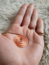 Load image into Gallery viewer, Hand wearing two copper rings with a spiral
